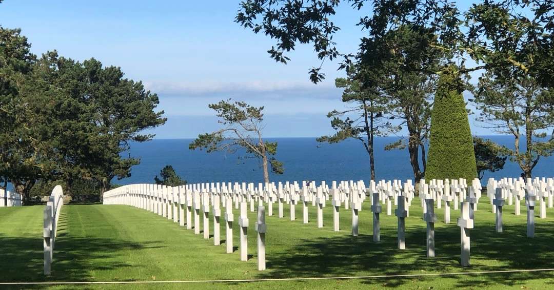 Rows of white crosses in cemetary overlooking water